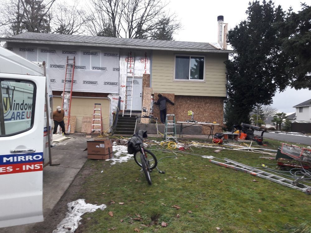 A white van is parked in front of a house under construction.