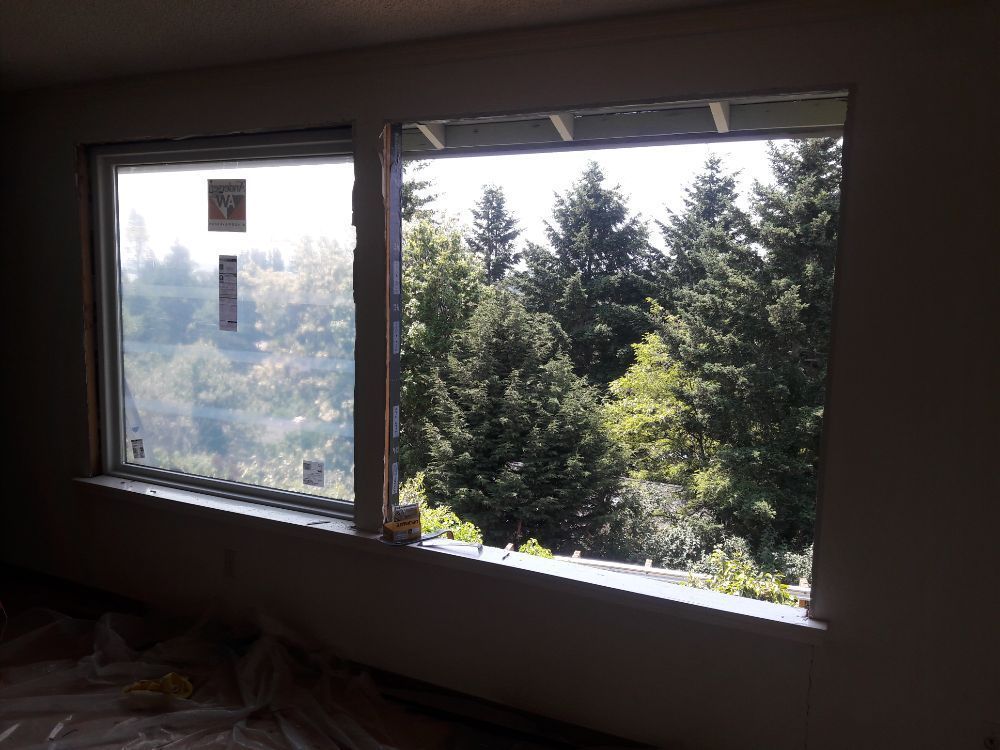 A large window in a room with a view of a forest.