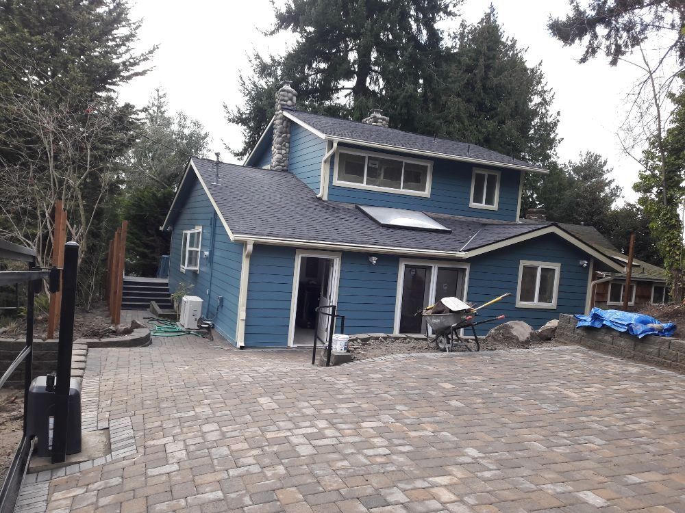 A blue house with a brick driveway in front of it