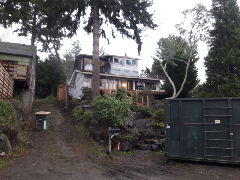 A dumpster sits in front of a house under construction