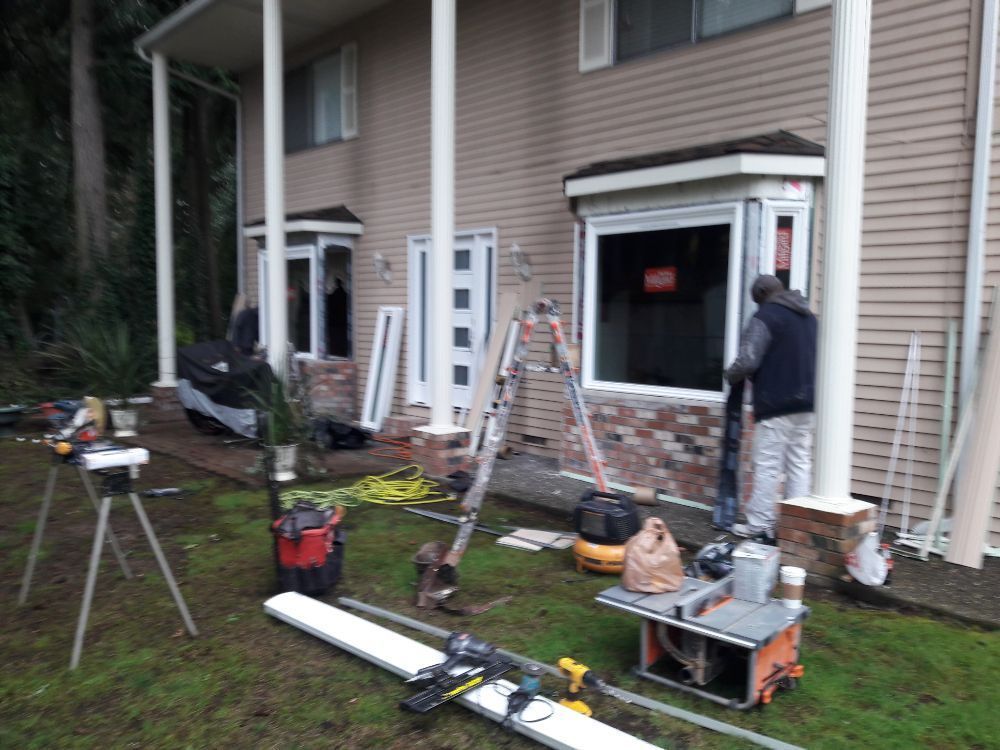 A man is installing a window on the side of a house.