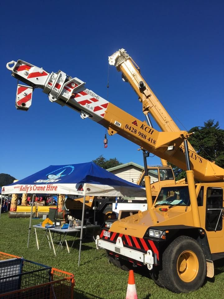 A Large Yellow Crane is Parked in a Grassy Field — Kelly's Crane Hire in Mossman, QLD
