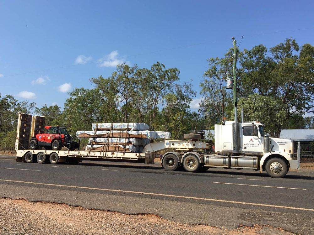 A Semi Truck is Carrying a Trailer With a Forklift on It — Kelly's Crane Hire in Mossman, QLD
