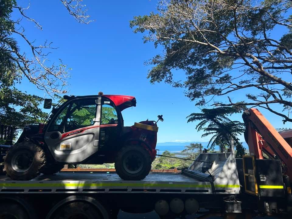A Forklift is Sitting on the Back of a Tow Truck — Kelly's Crane Hire in Port Douglas, QLD