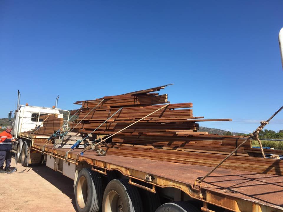 A Truck is Carrying a Large Stack of Wood — Kelly's Crane Hire in Mossman, QLD