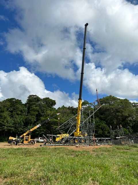 A Large Yellow Crane is Sitting in the Middle of a Grassy Field — Kelly's Crane Hire in Mossman, QLD