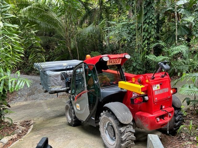 A Red Tractor is Parked on the Side of a Dirt Road — Kelly's Crane Hire in Mossman, QLD