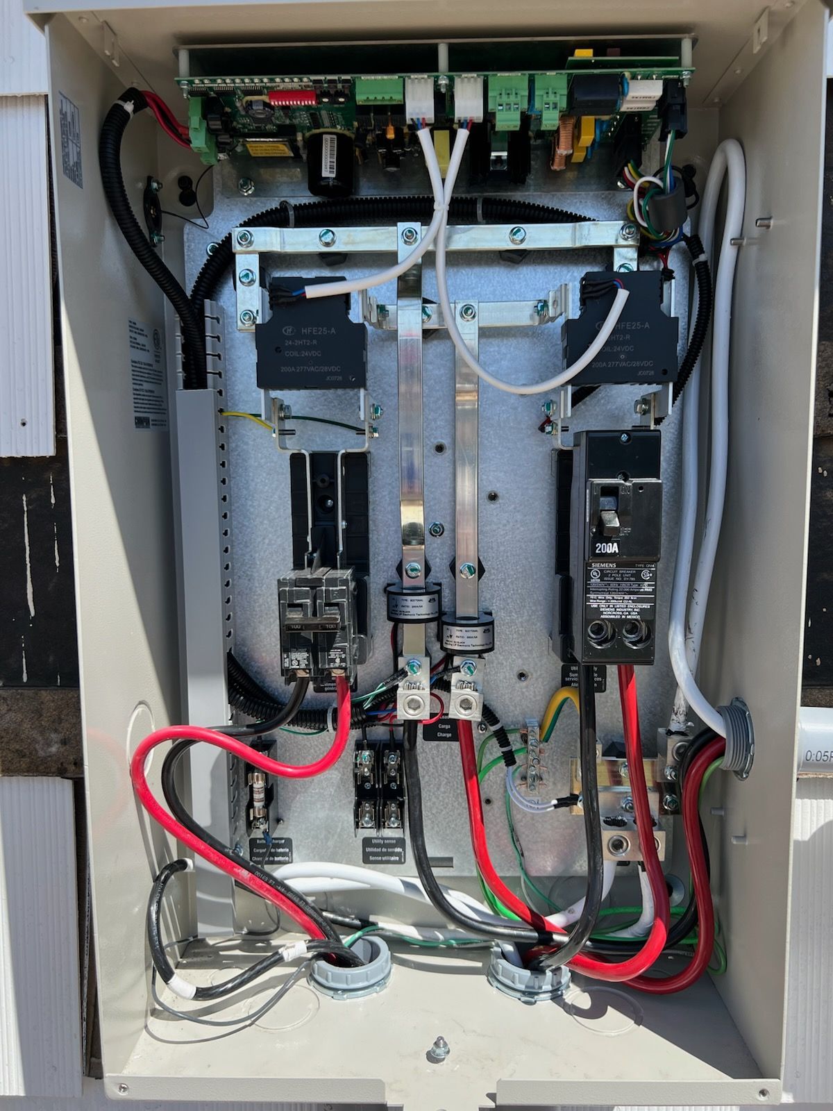 Open electrical box with circuits, wires, and a control board. Red and black wires are prominent.