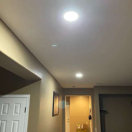 Hallway with recessed ceiling lights; an open doorway is visible in the distance.