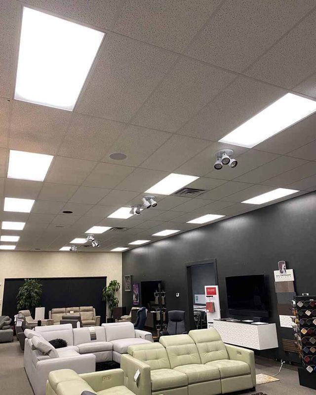 A furniture store interior with couches and overhead lighting. Gray walls, displays and customers visible.