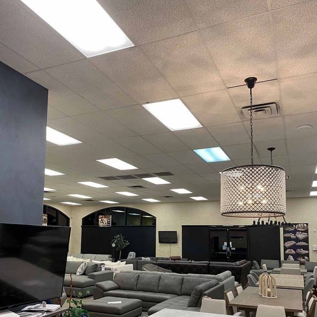 Interior of a furniture store with various displays under bright ceiling lights.