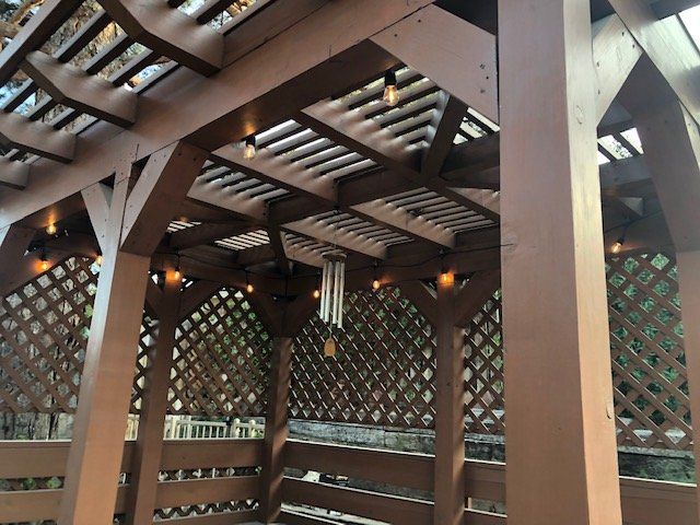 Brown wooden pergola with latticework and string lights, viewed from below.