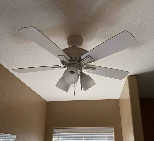White ceiling fan with four blades and light fixtures on a white ceiling.