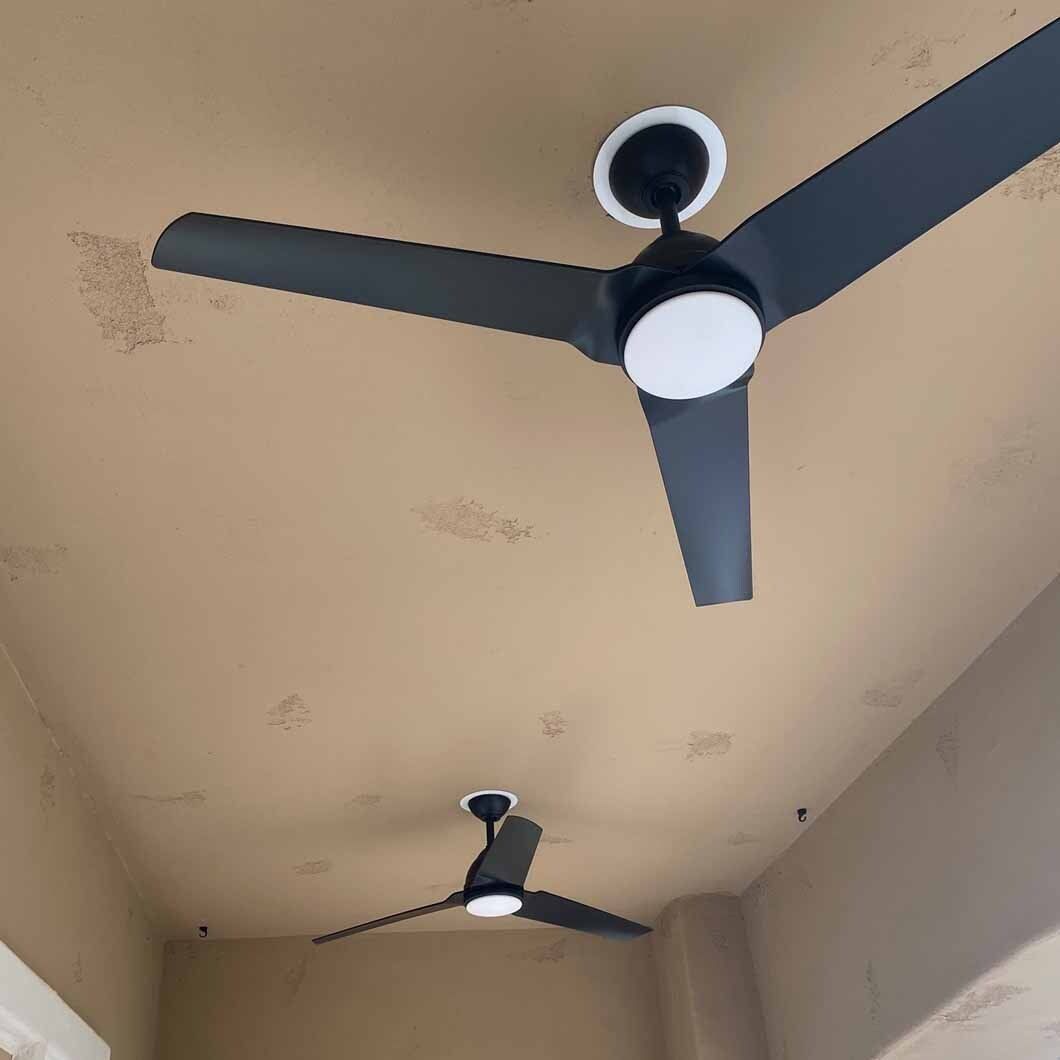 Two black ceiling fans with lights on a textured beige ceiling.