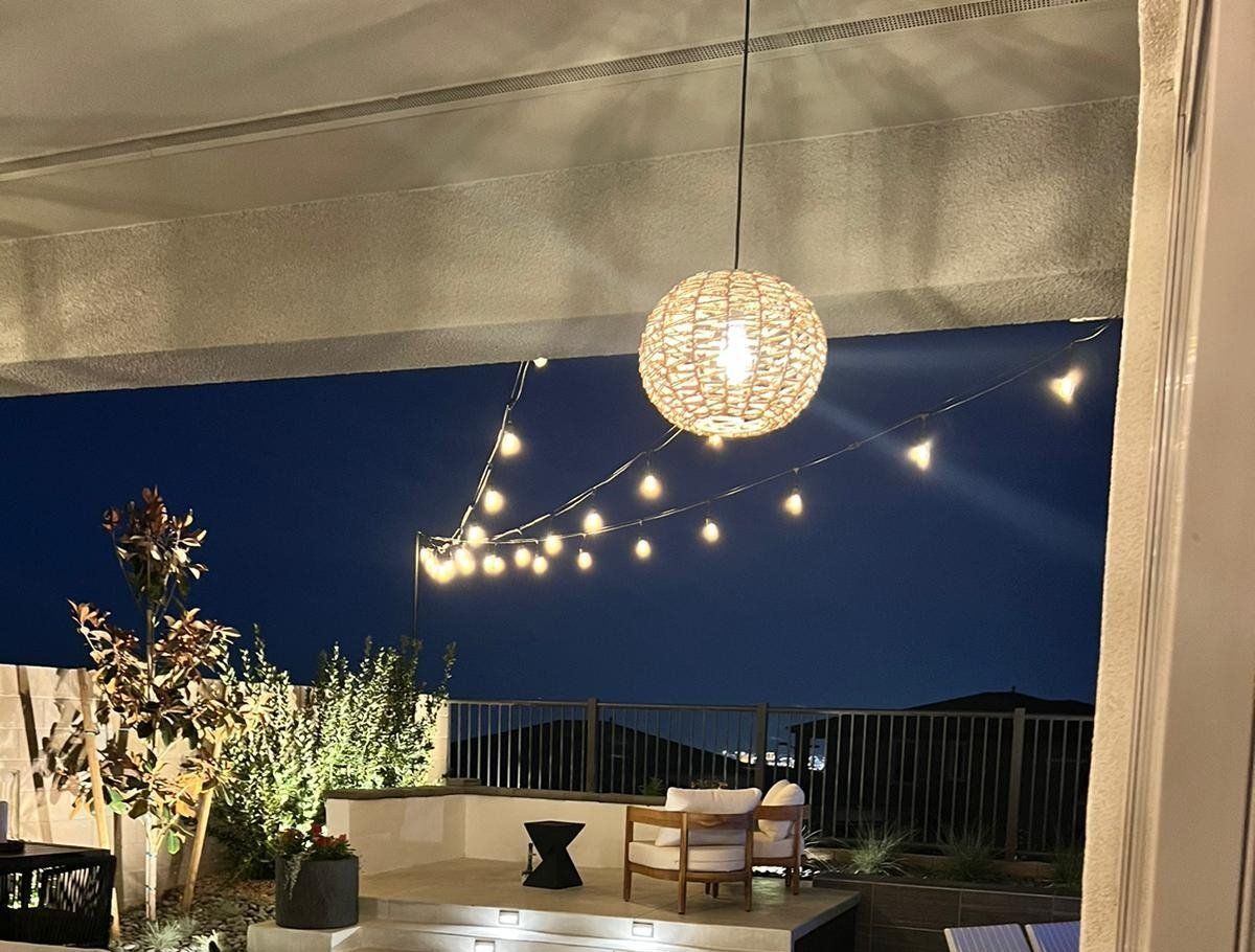 Outdoor patio at night with string lights and a hanging orb light.