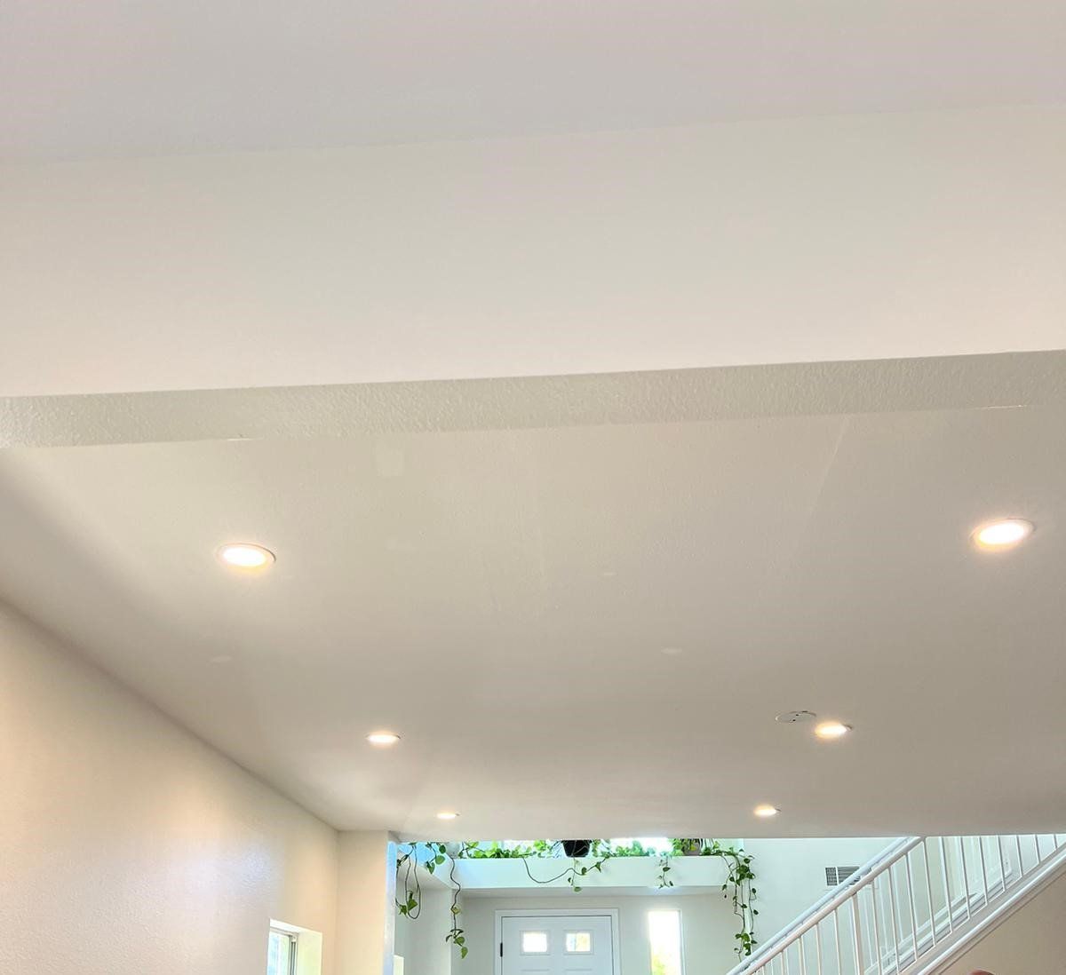 White ceiling with recessed lights, leading to a doorway decorated with greenery.