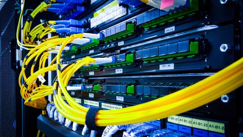 Server rack with various cables and connectors, yellow cables looped in front.