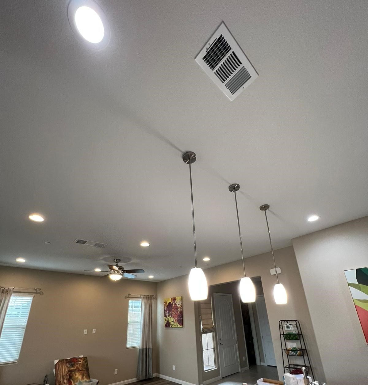 Interior view of a ceiling with recessed lights, pendant lamps, and a vent.