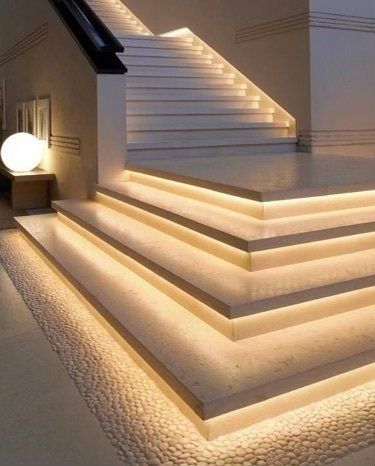 Lit staircase with warm lighting; pebble flooring.