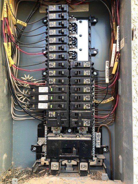 Electrical panel with breakers and wiring, installed in an outdoor enclosure.
