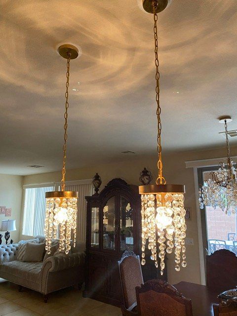 Two gold pendant lights with crystal strands hanging over a dining area.