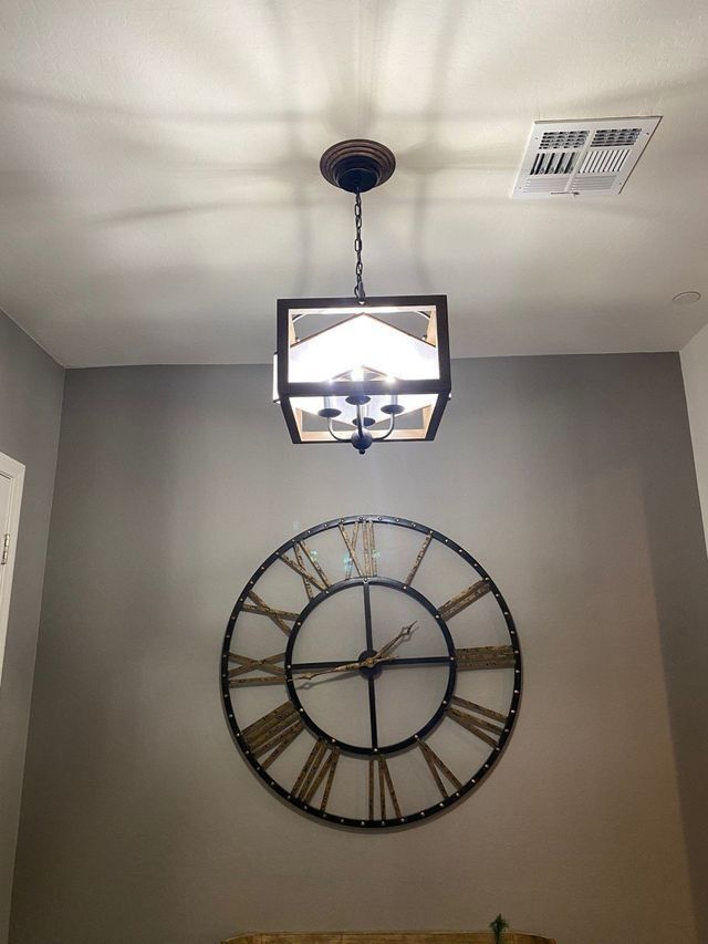 Ceiling light over a large clock on a gray wall.