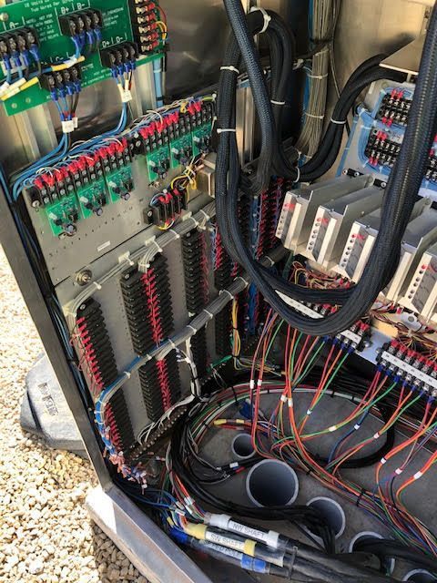 Interior of an electrical cabinet showing numerous wires and circuit boards, with various colored connectors.