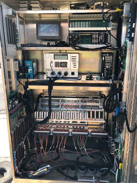 Open metal cabinet with electronic equipment, wires, and a monitor.