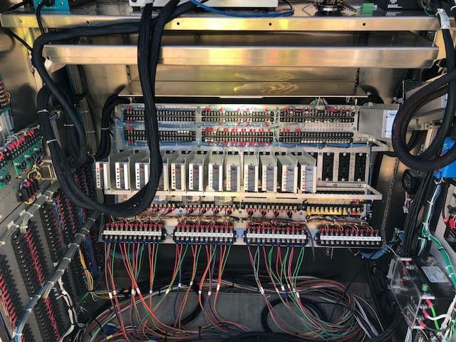Inside of a metal cabinet filled with electrical wiring, controllers, and terminal blocks.