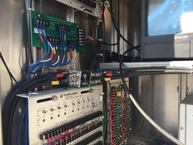 Electronics equipment inside a metal cabinet, with circuit boards, wires, and a monitor.