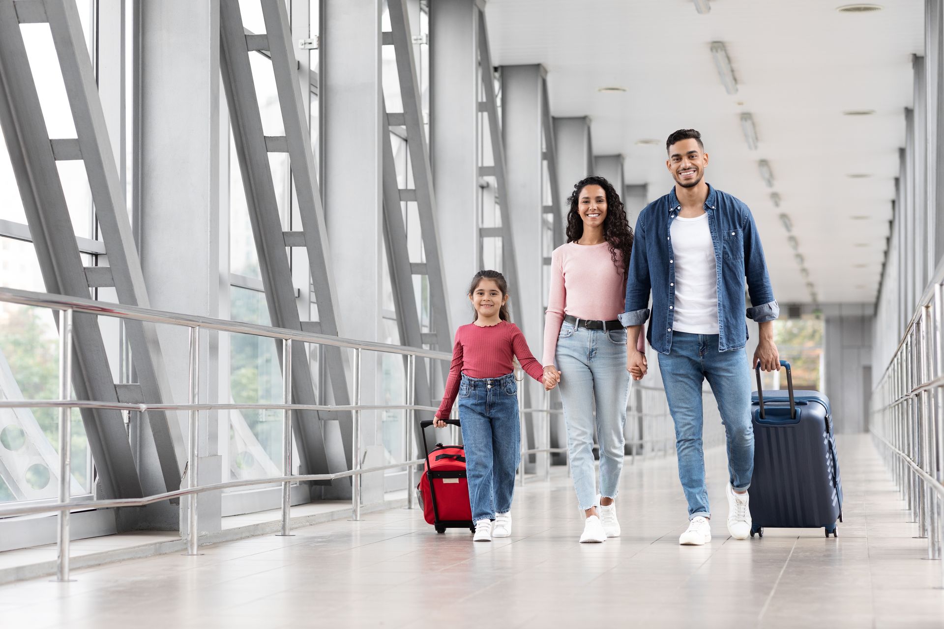 A family is walking through an airport with luggage.