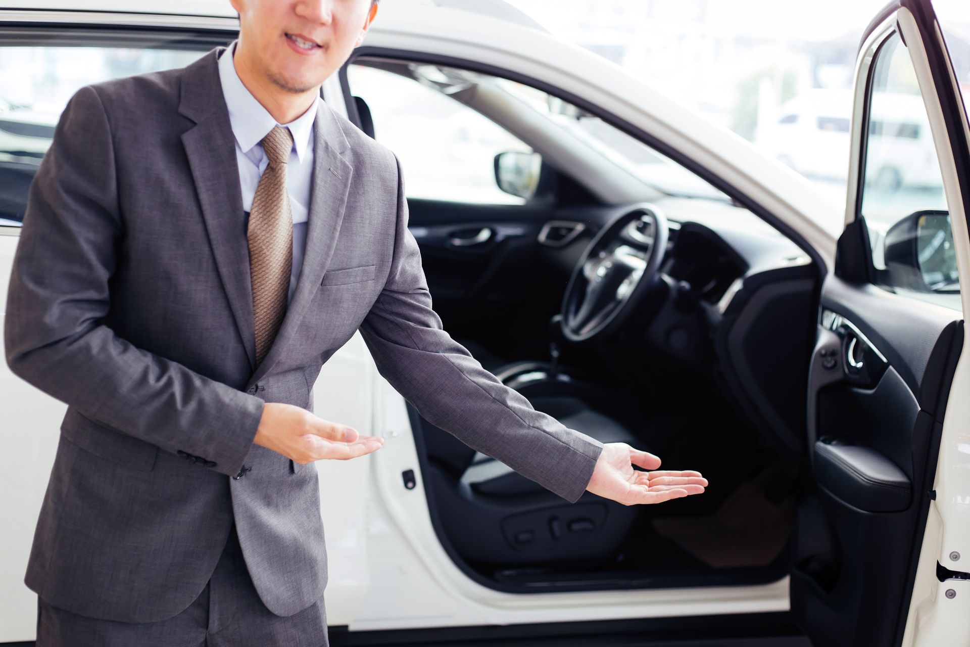 A man in a suit and tie is standing next to a white car.