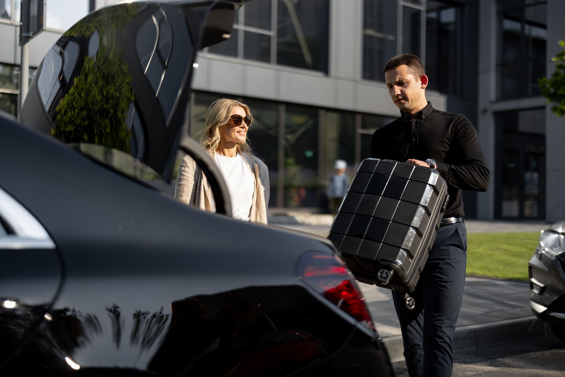 A man is carrying a suitcase into the back of a car.