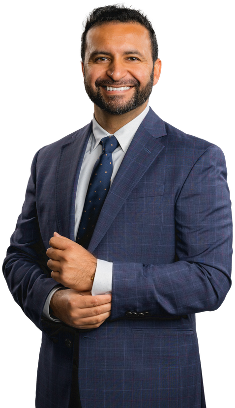 A man in a suit and tie is standing with his hands folded.
