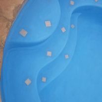 a blue swimming pool with white tiles on the steps .