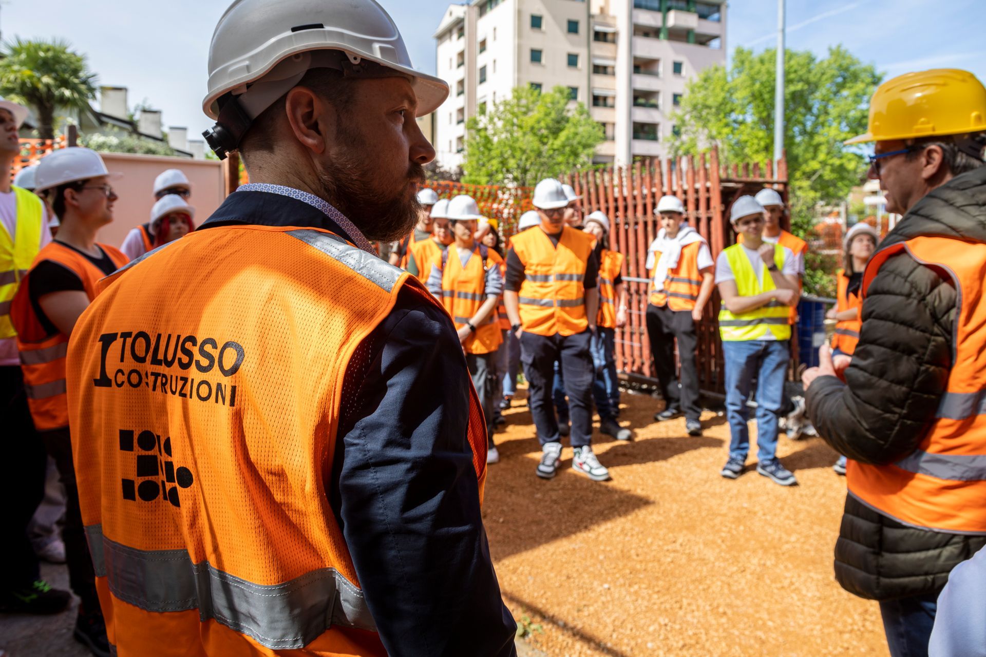 Un membro dello staff Tolusso Costruzioni di spalle osserva il cantiere, di fronte a lui i colleghi in ascolto