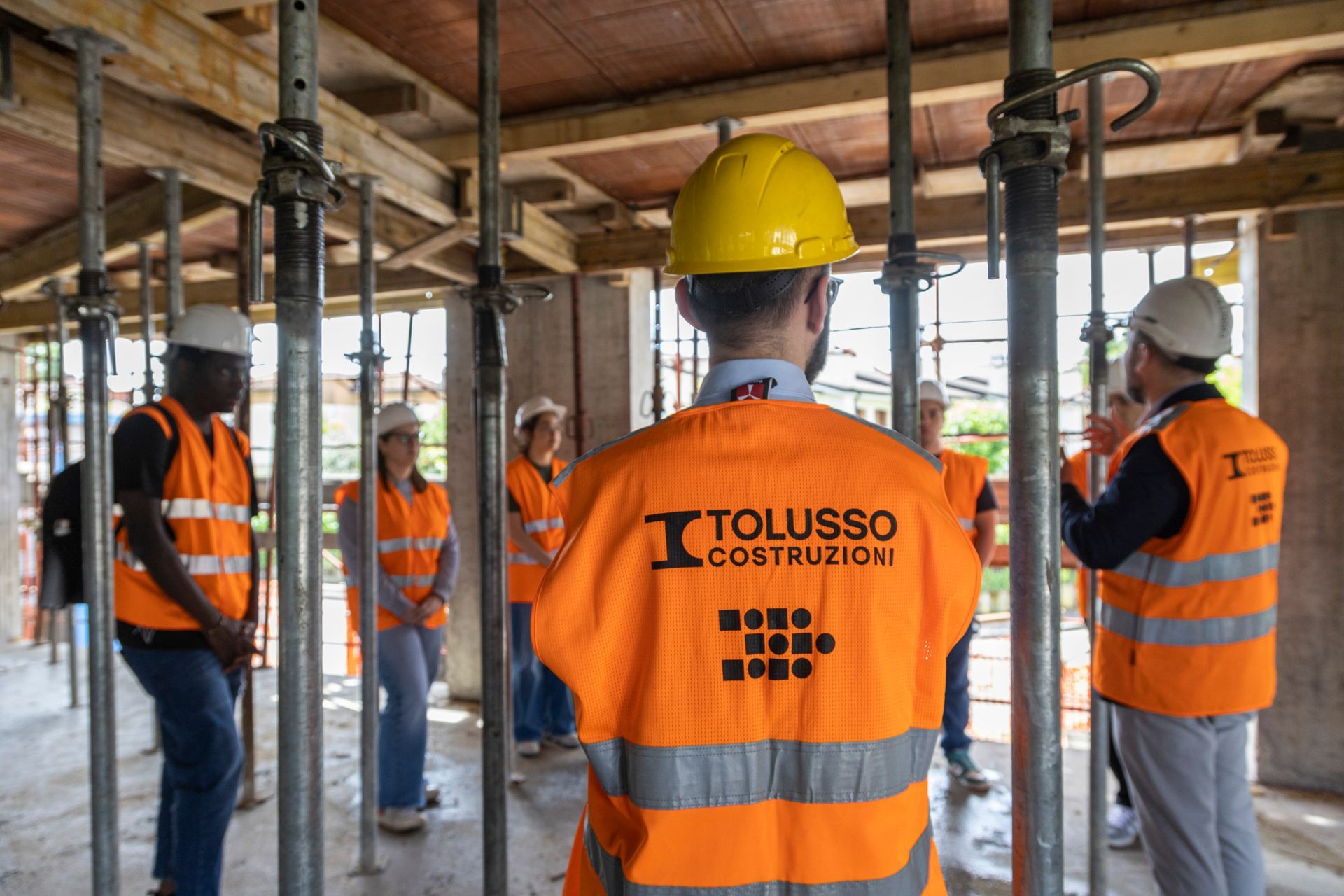 Dipendente della Tolusso Costruzioni di spalle in cantiere ascolta l'intervento dei colleghi