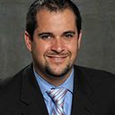 A man in a suit and tie is smiling for the camera.