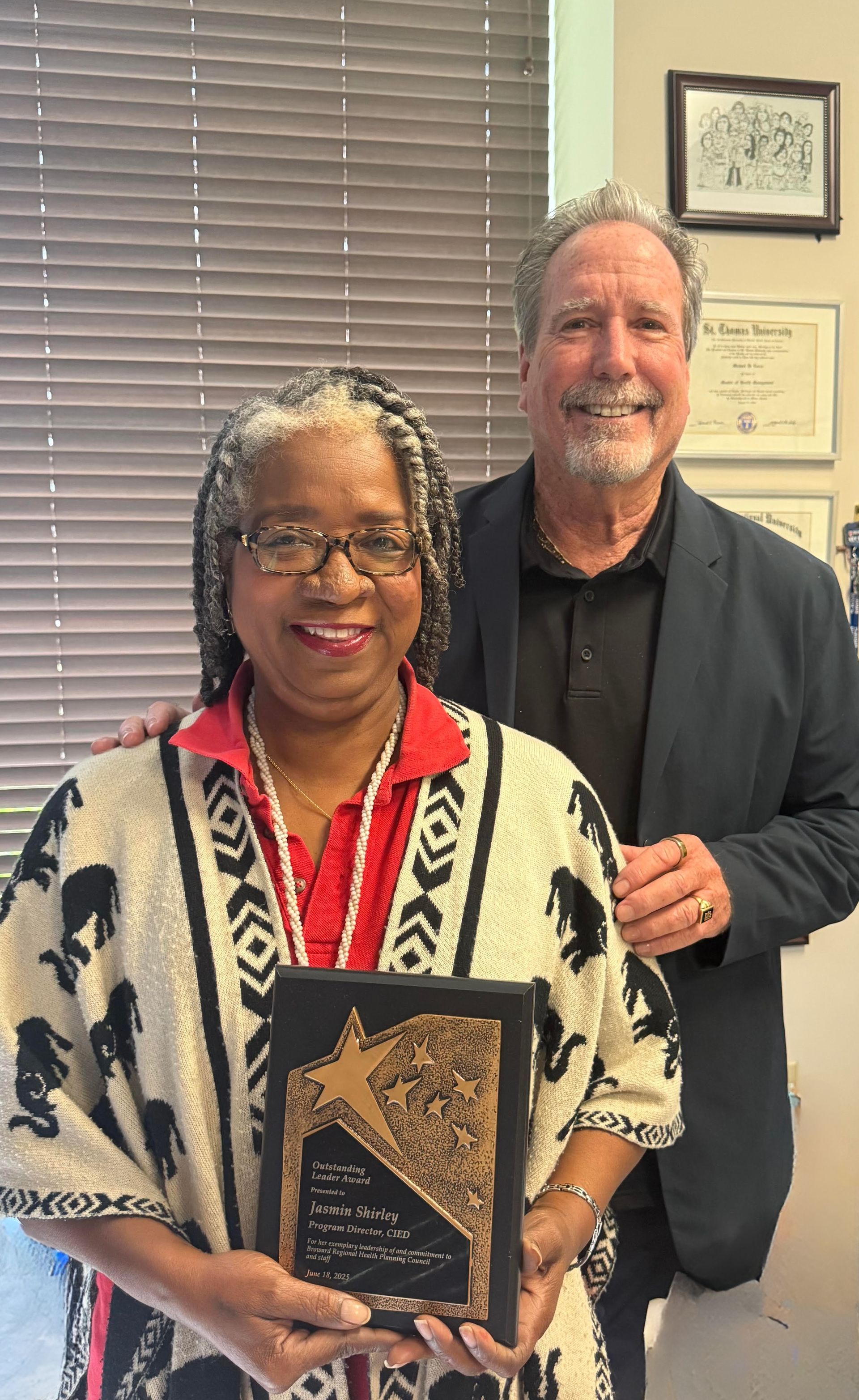 A man and a woman are standing next to each other holding a plaque.