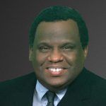 A man in a suit and tie is smiling for the camera.