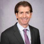 A man in a suit and tie is smiling for the camera.