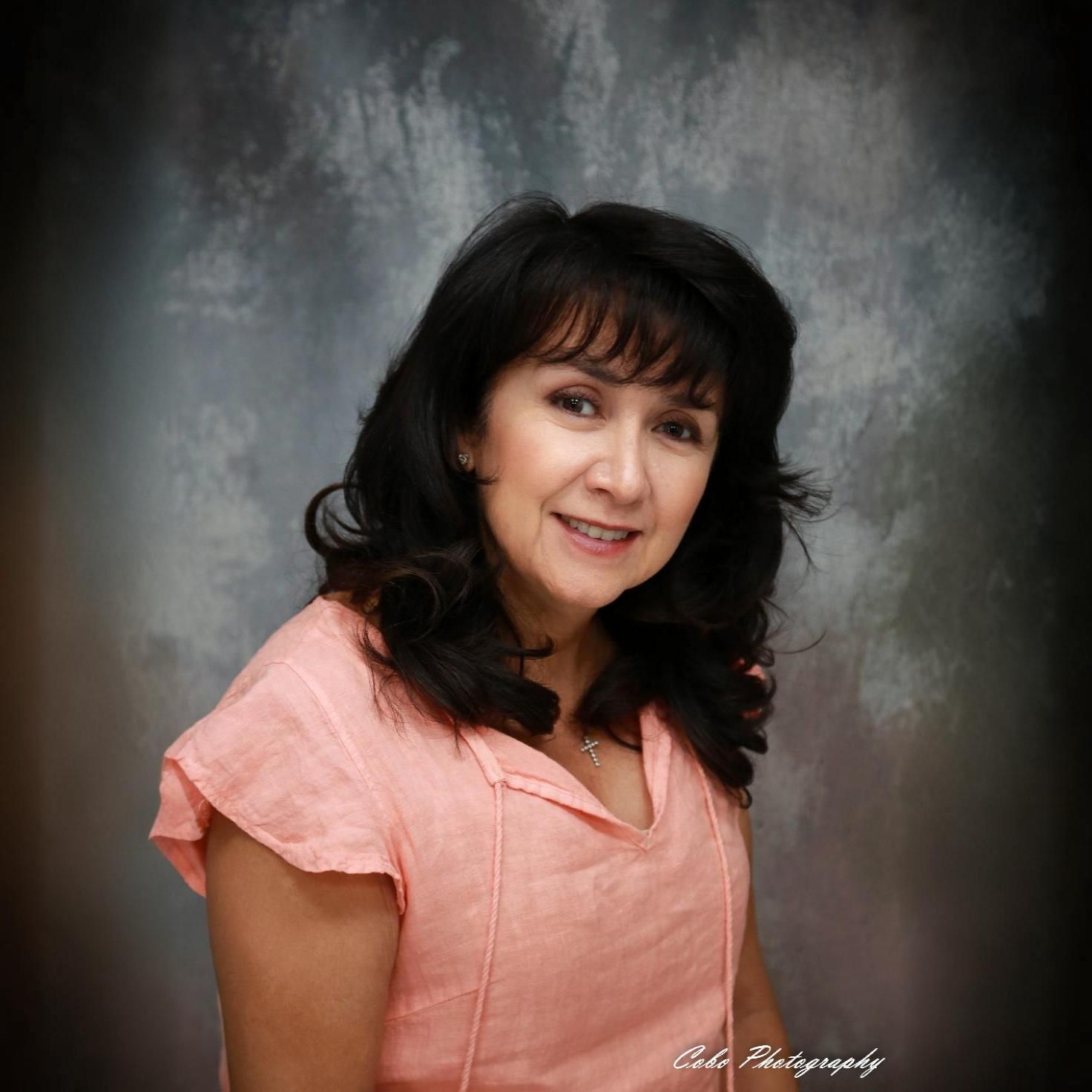A woman in a pink shirt is smiling for the camera