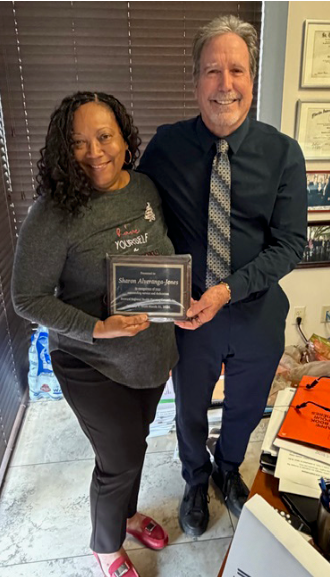 A man and a woman are standing next to each other holding a plaque.