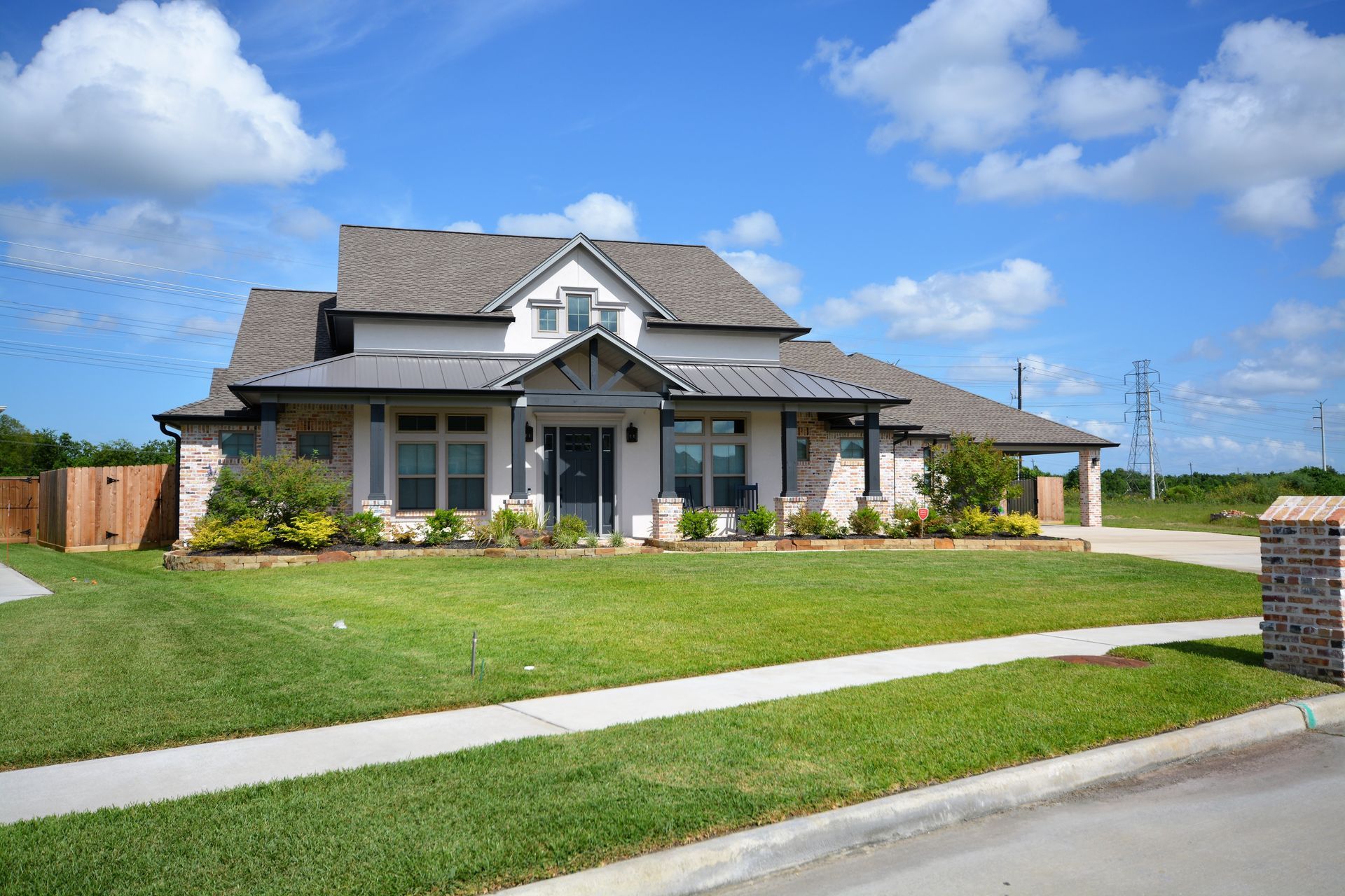 A large white house with a gray roof is sitting on top of a lush green lawn.