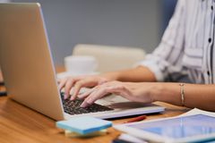 A woman is typing on a laptop computer at a desk.