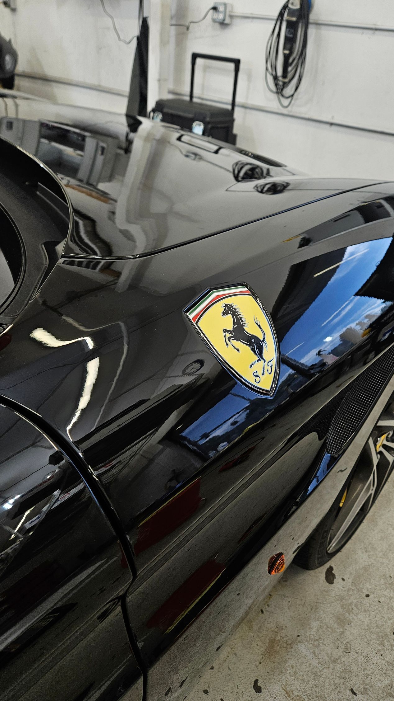 Black Ferrari sports car with yellow and black emblem on front panel.