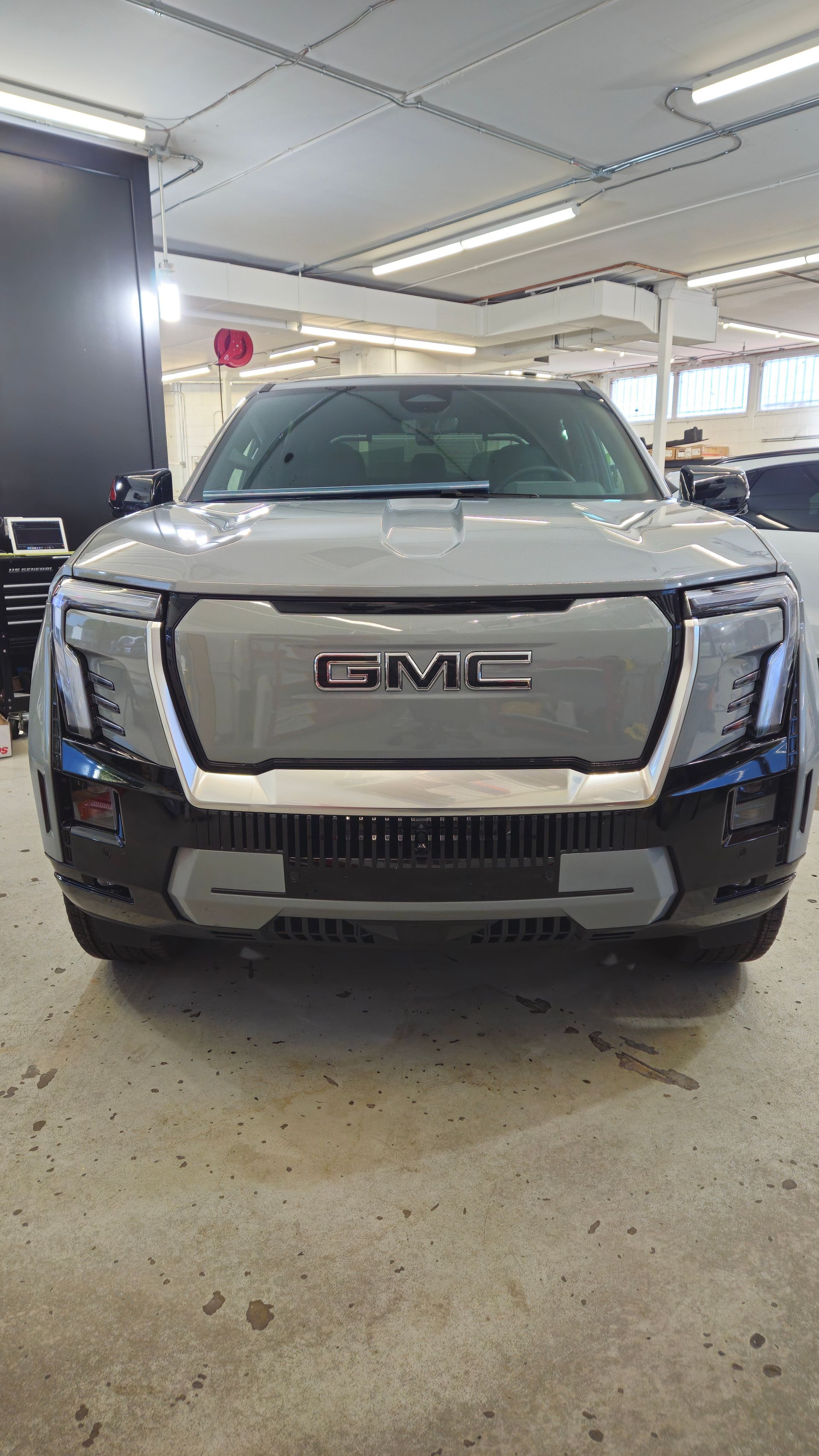 Gray GMC SUV in a garage, front view. The GMC logo is visible.