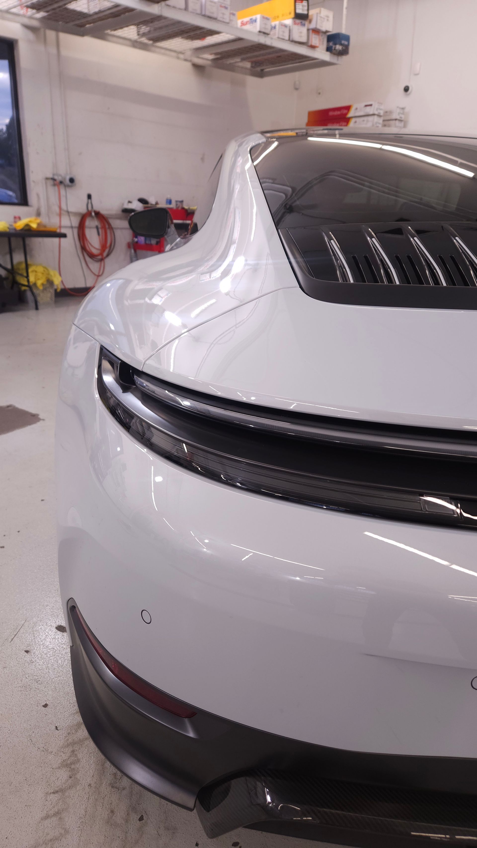 White Porsche sports car, rear view, in a garage setting.