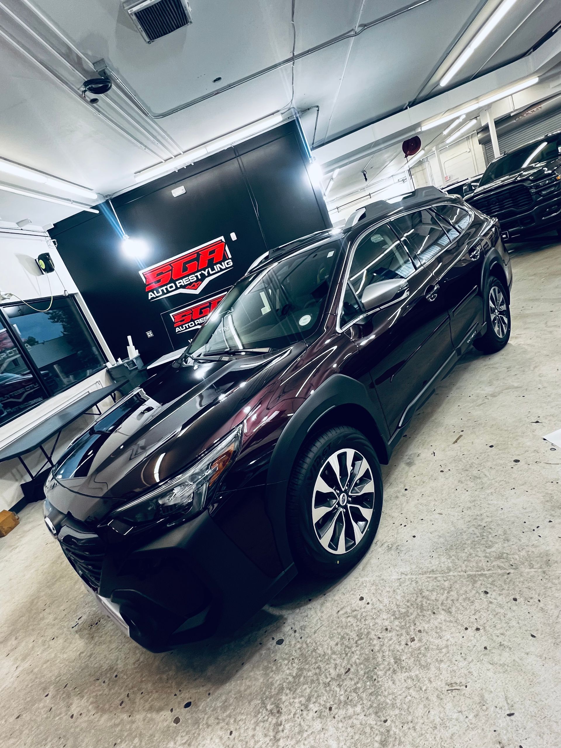 Dark maroon Subaru Outback in a garage, shiny and clean.
