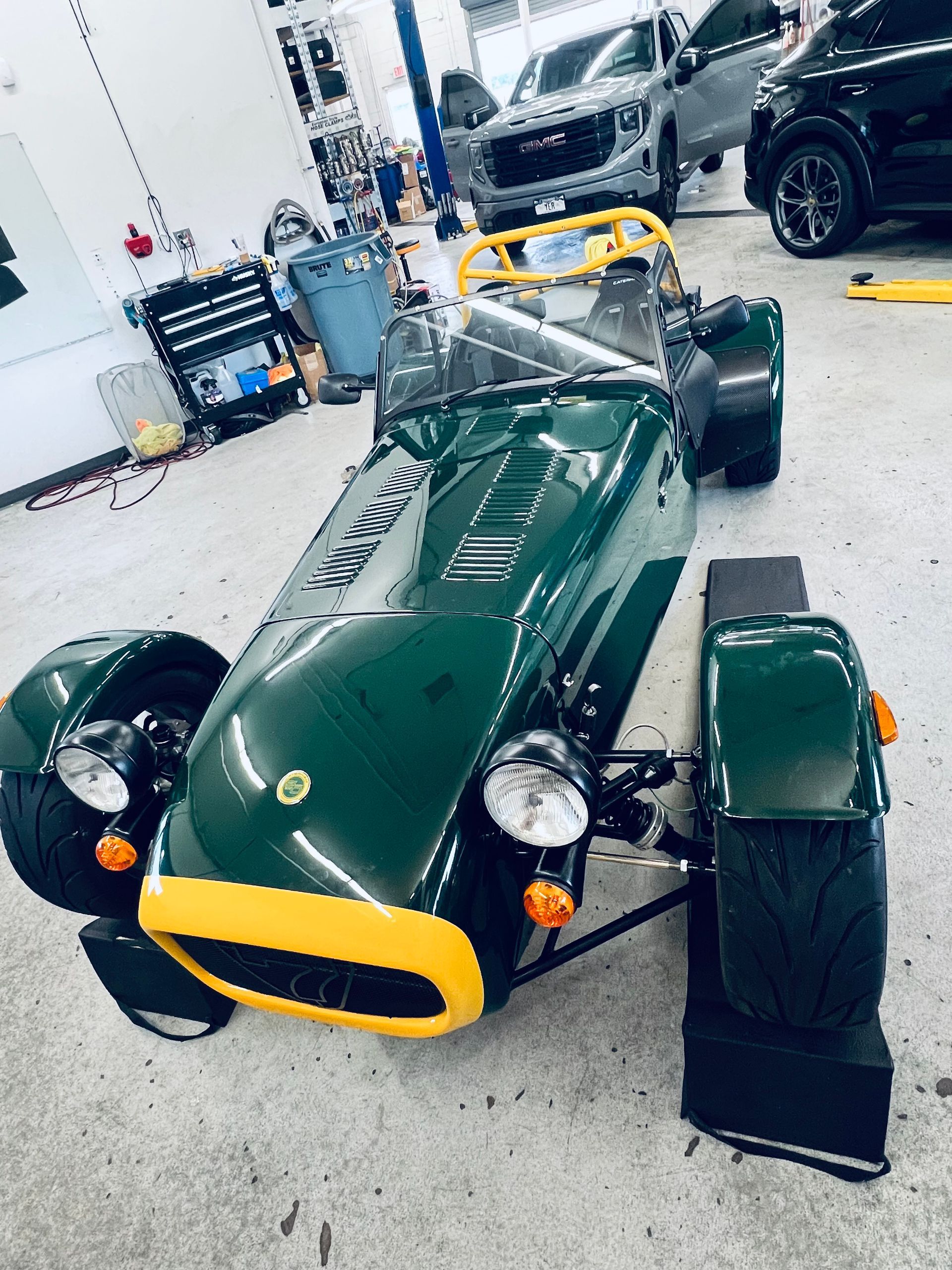 Green and yellow open-wheel sports car in a garage.